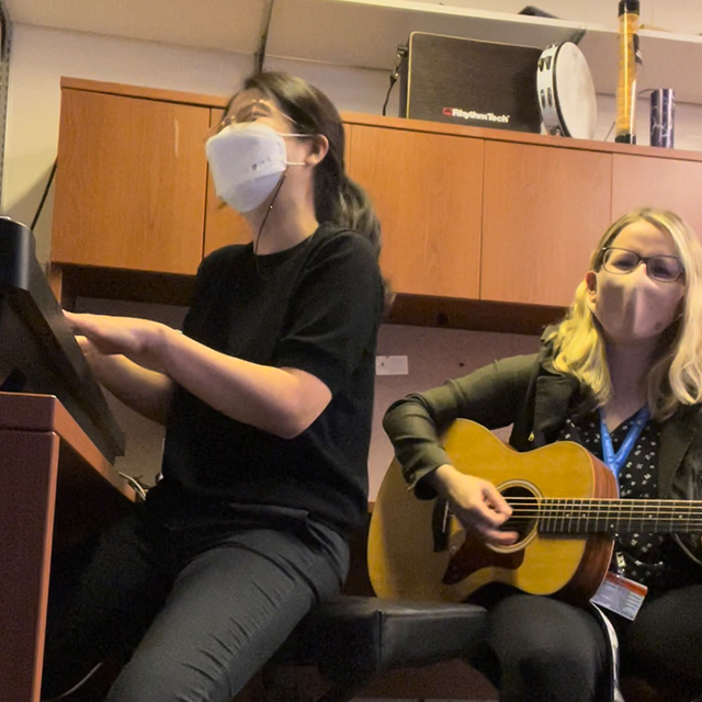 Music therapist Kerry Devlin and postdoctoral fellow Kyurim Kang play music in their office.
